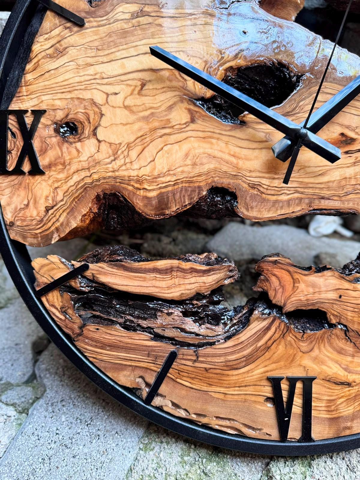 Large olive wood clock on a white wall, natural live edge grain visible across the full wooden face