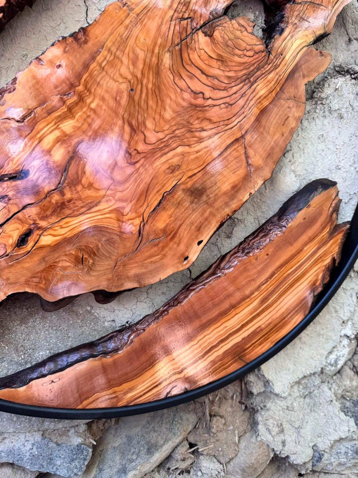 Detail of the black metal frame edge against the raw live-edge wood