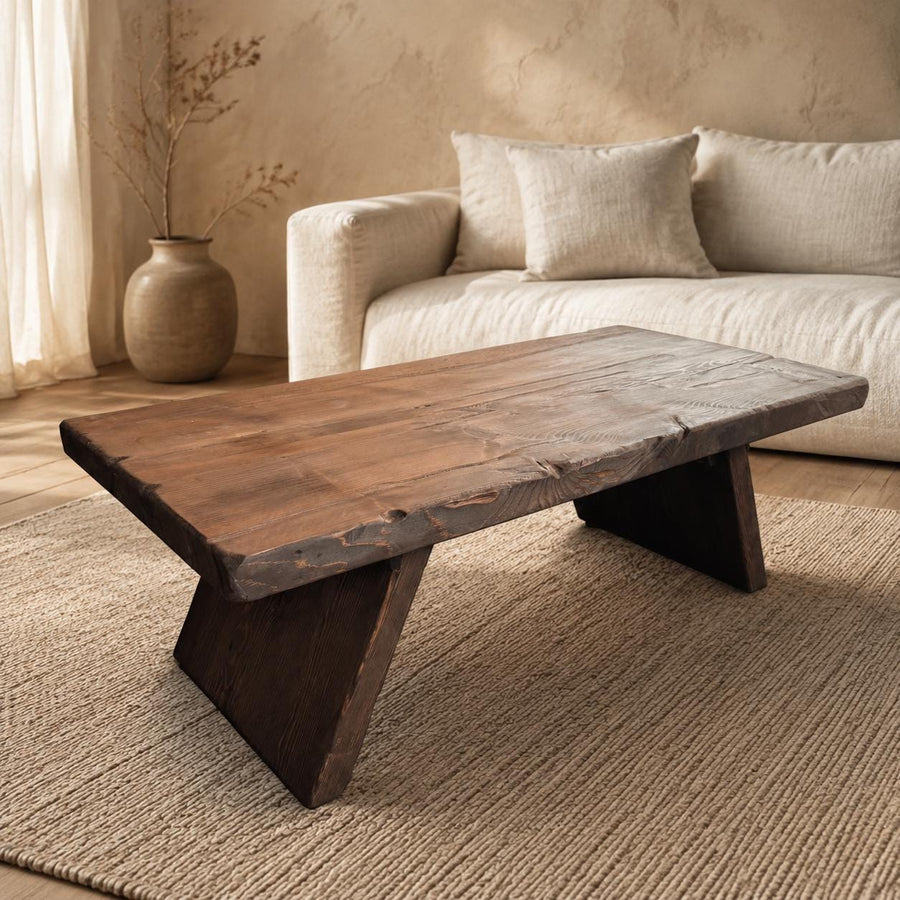 Handmade solid cedar live edge coffee table in a warm Japandi living room, showing the thick top and angled slab legs